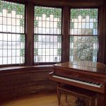 A vintage piano and stained glass windows inside Thistle Cottage.